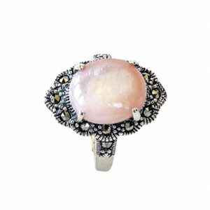 A silver ring featuring a round pink stone and small dark stones.